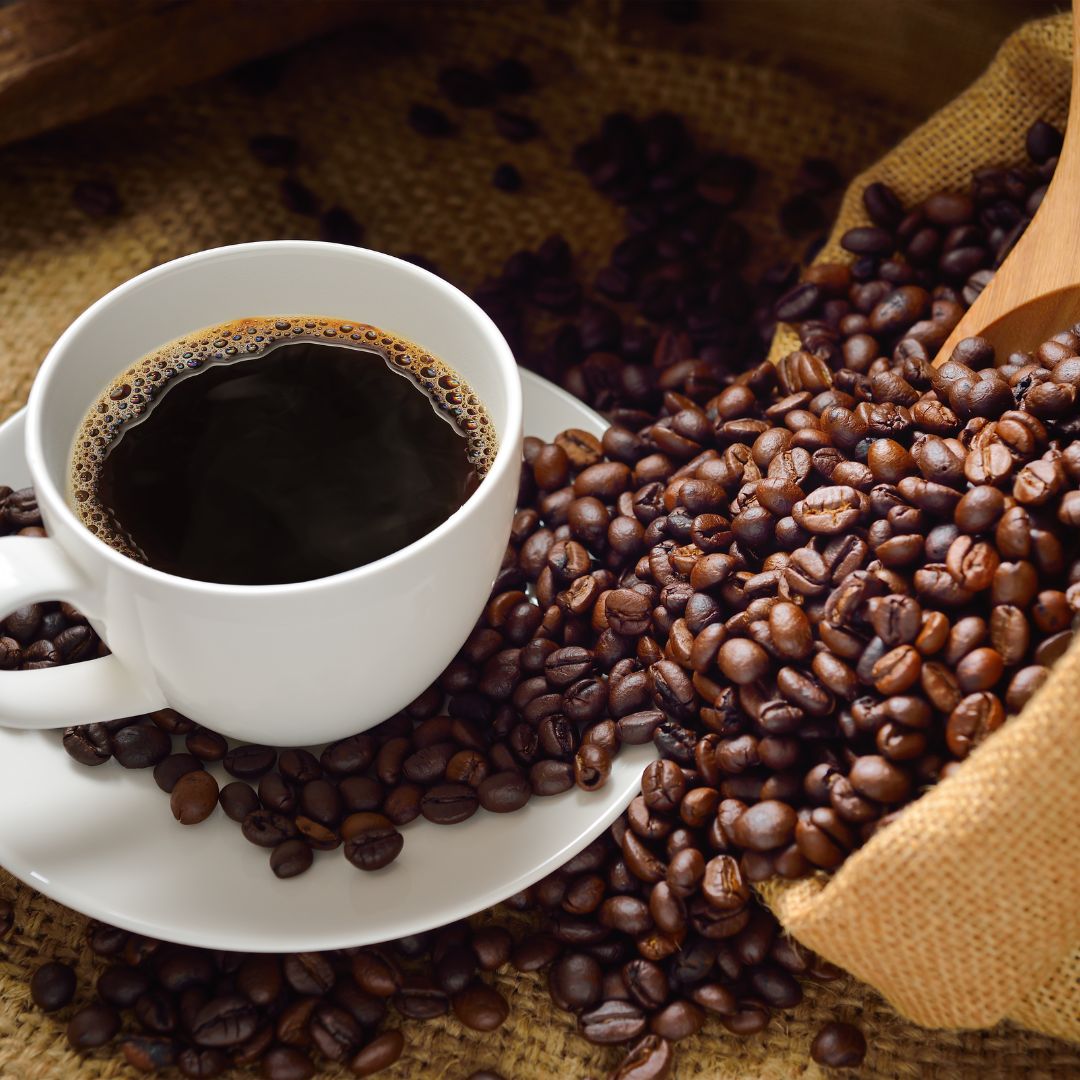 Een bakje koffie et allemaal koffiebonen eromheen.