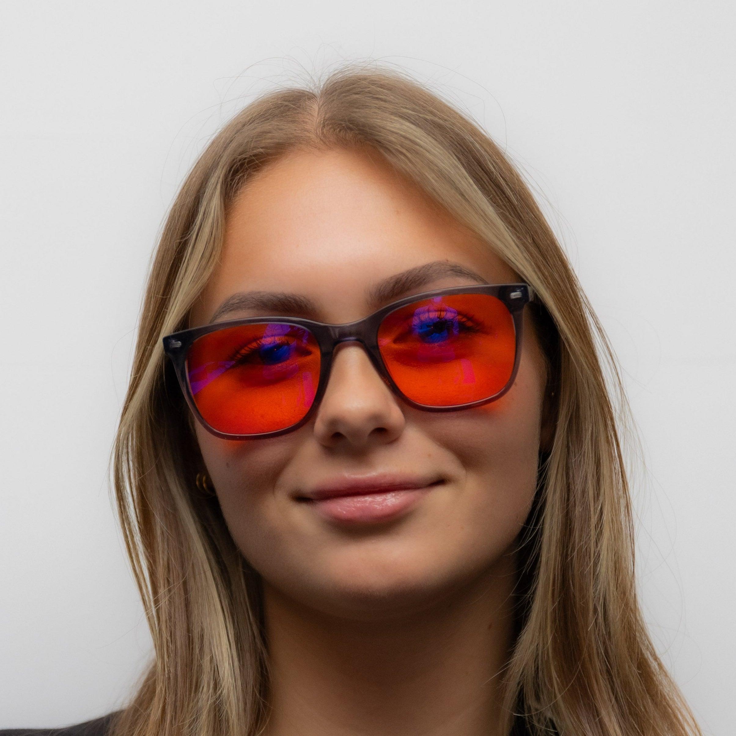 Model met de Alina blauw licht blokker met rode lenzen op.
